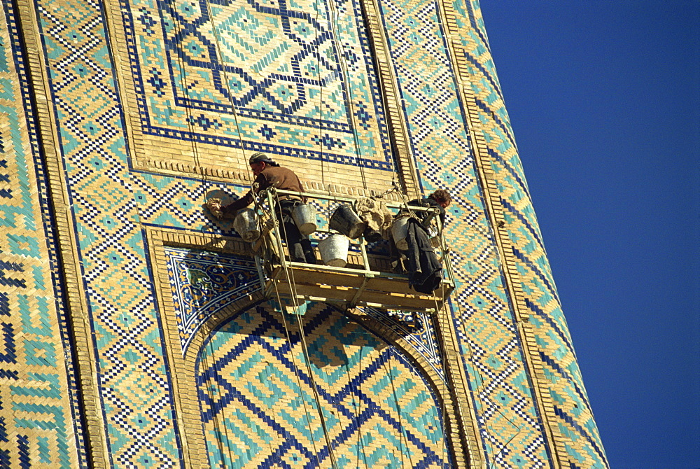 Workers in cradle refurbishing the 17th century Sher Dor Madressa, Registan Square, Samarkand, Uzbekistan, Central Asia, Asia