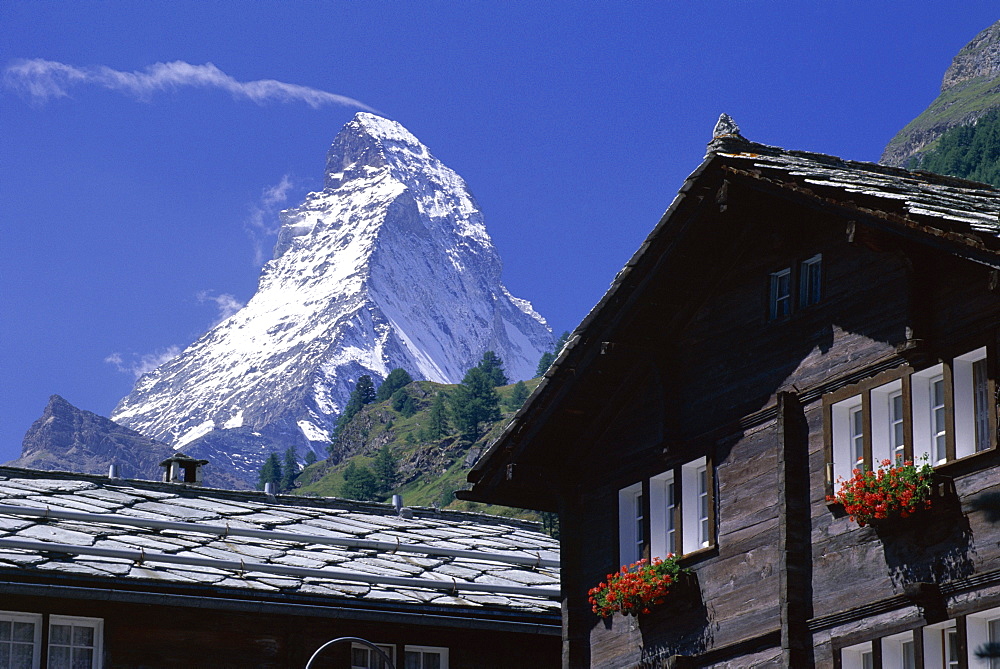 The peak of the Matterhorn mountain towering above chalet rooftops, Zermatt, Valais, Swiss Alps, Switzerland, Europe