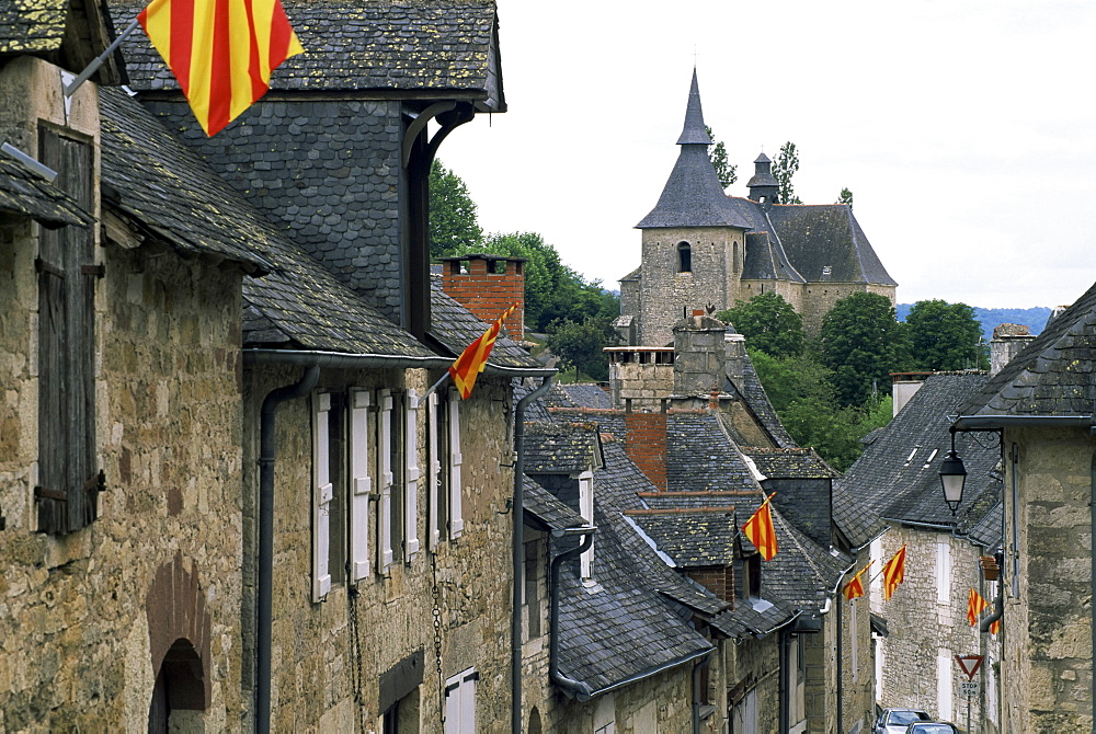 View along village street to church, with colourful flags, Turenne, Correze, Limousin, France, Europe