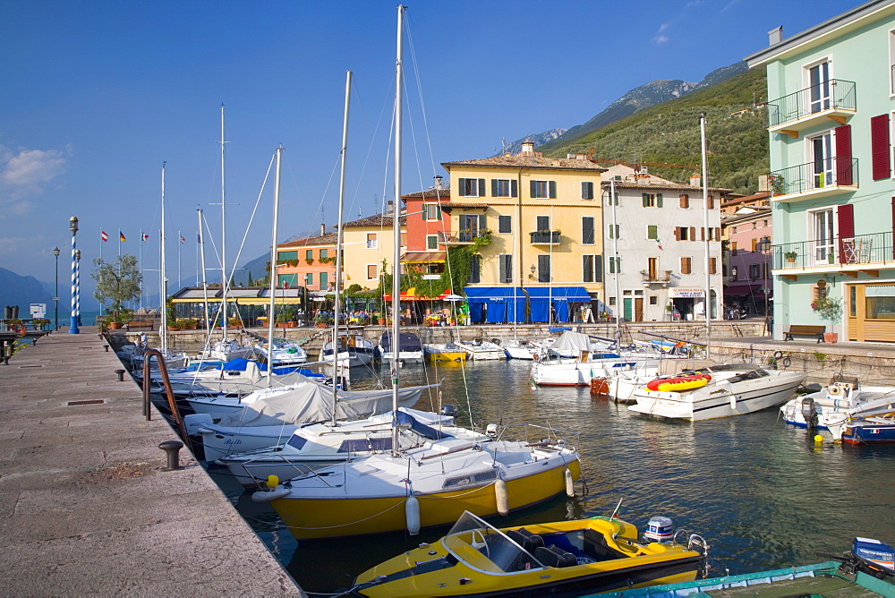 View across the harbour to colourful houses on the shore of Lake Garda, Castelletto di Brenzone, Verona, Veneto, Italy, Europe