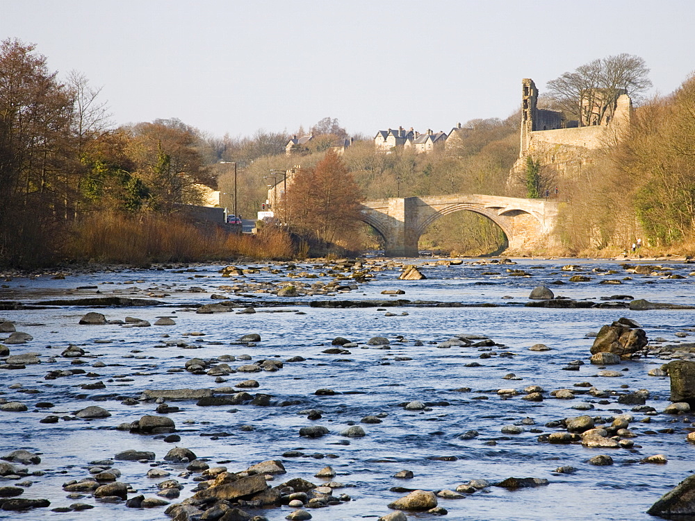 View along the boulder-strewn River Tees to the ruined castle and 16th century County Bridge, Barnard Castle, County Durham, England, United Kingdom, Europe