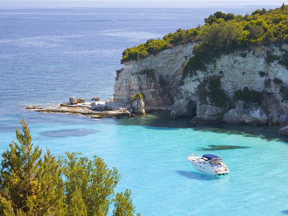 View from hillside over secluded Voutoumi Bay, solitary boat at anchor, Antipaxos, Paxi, Corfu, Ionian Islands, Greek Islands, Greece, Europe