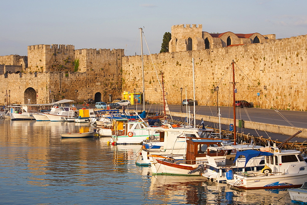 View across tranquil Kolona Harbour to the city walls, sunrise, Rhodes Town, Rhodes, Dodecanese Islands, South Aegean, Greece, Europe