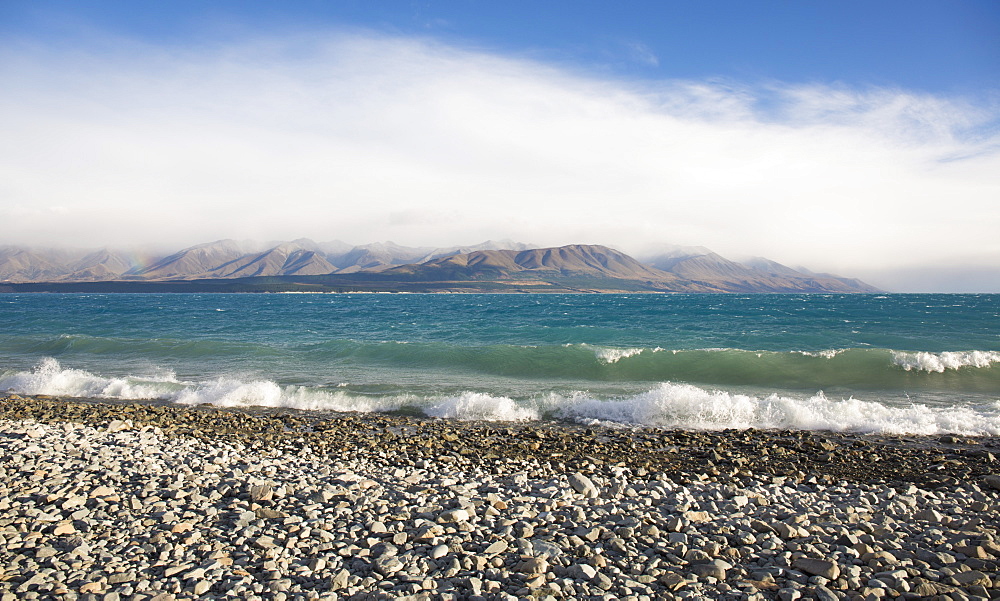 View from rocky shoreline across the stormy waters of Lake Pukaki, near Twizel, Mackenzie district, Canterbury, South Island, New Zealand, Pacific