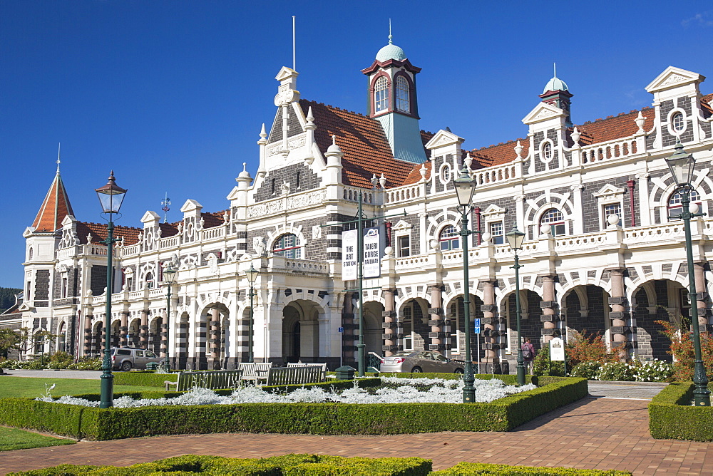 View from gardens to the imposing facade of Dunedin Railway Station, Anzac Square, Dunedin, Otago, South Island, New Zealand, Pacific