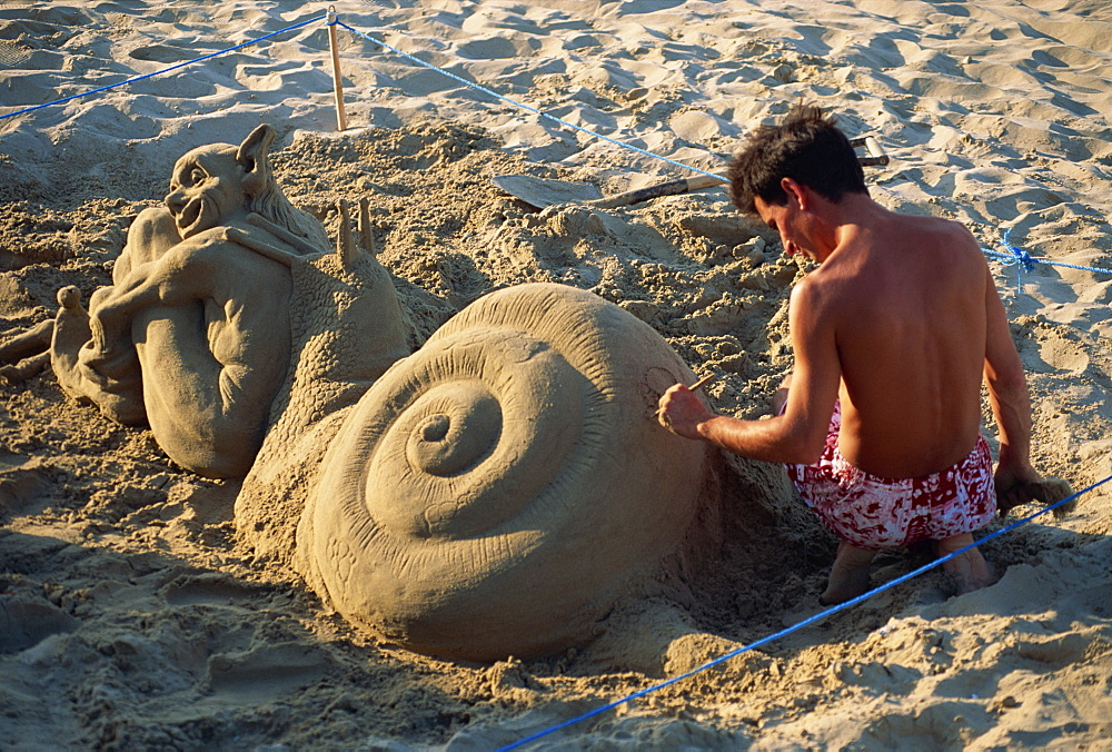 Man working on sand sculpture on beach, Valencia, Spain, Europe