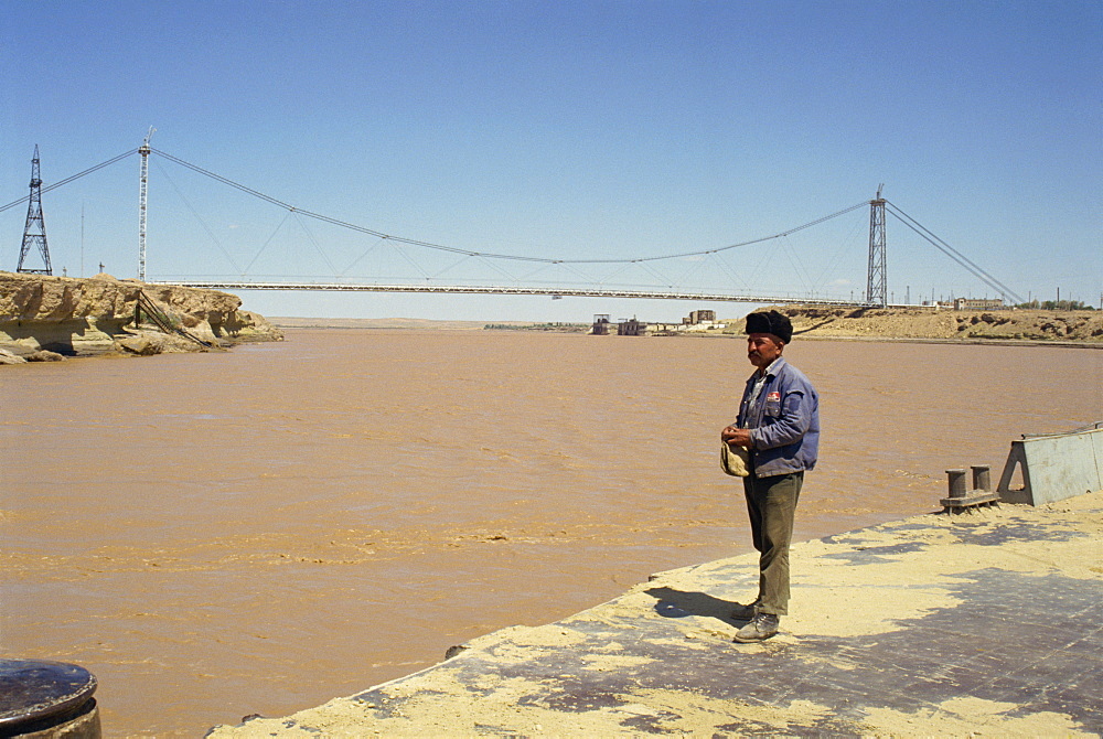 Man standing on the river bank in front of a bridge over the River Oxus (Amu Darya), between Uzbekistan and Turkmenia, Central Asia, Asia