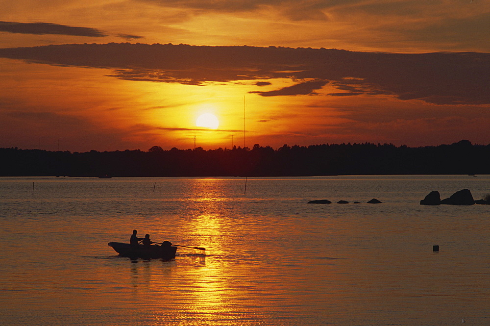 Row boat silhouetted over Dragso bay at sunset in summer, at Karlskona, Sweden, Scandinavia, Europe