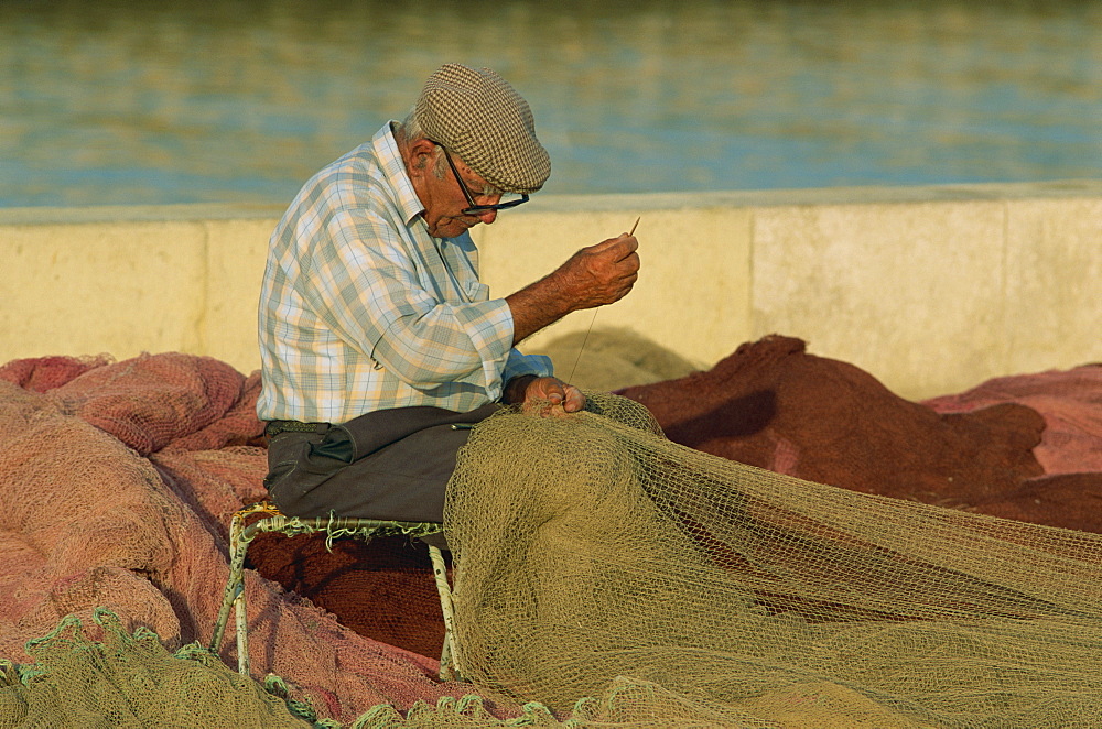 Fisherman fixing nets on beach, The Algarve, Portugal, Europe