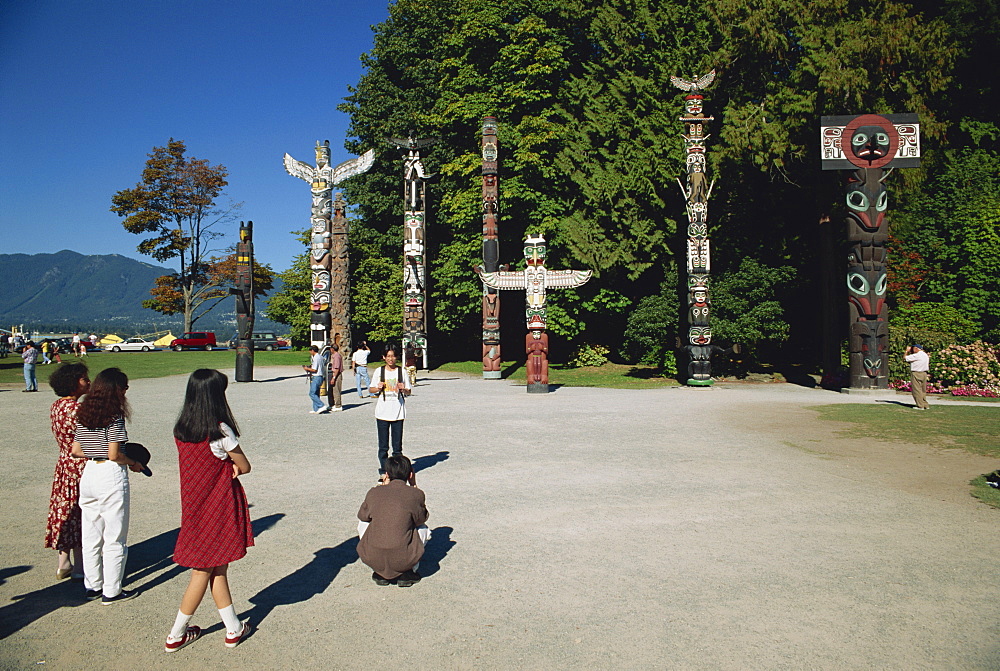 Tourists visiting Totems at Stanley Park in Vancouver, British Columbia, Canada, North America