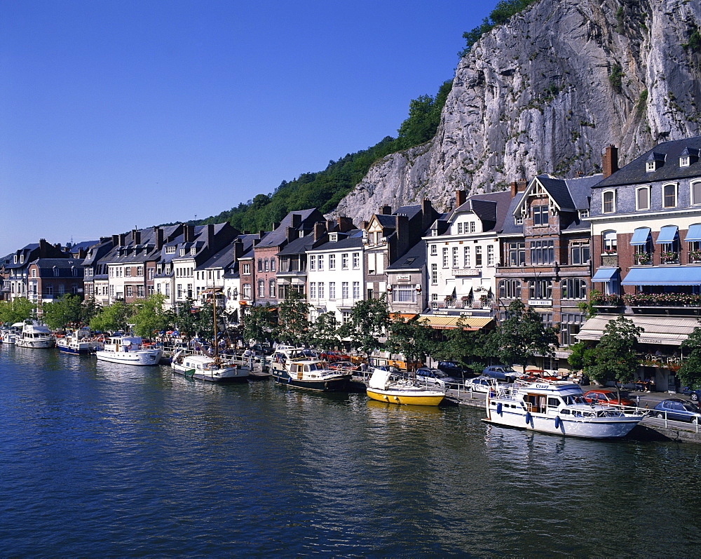 Boats line the waterfront on the River Meuse in the old town of Dinant in the Ardennes, Belgium, Europe