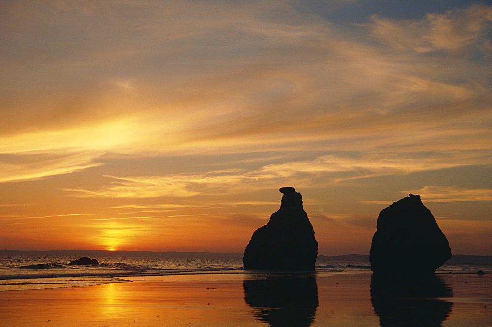 Rocks on the coastline silhouetted at sunset at Praia de Alvor in the Algarve, Portugal, Europe