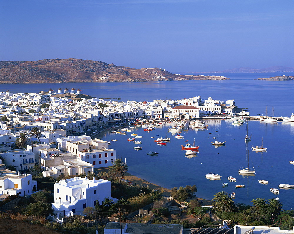 Boats in the harbour and windmills on the coast, with the sea and hills in the background, on Mykonos, Cyclades Islands, Greek Islands, Greece, Europe