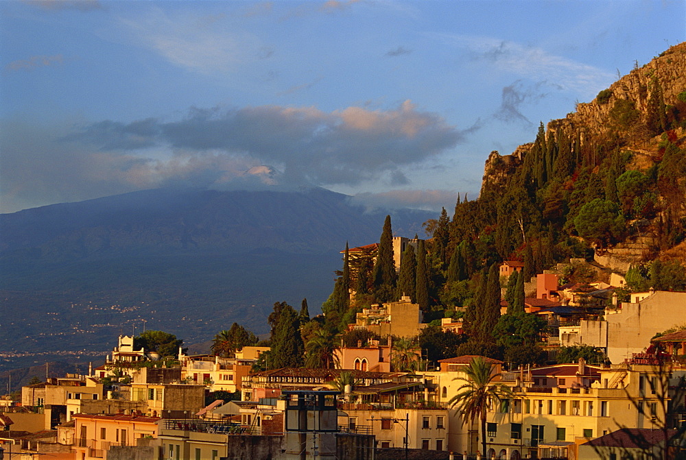 Aerial view over town of Taormina at dusk, including Mount Etna, 3340m, in distance, Sicily, Italy, Europe