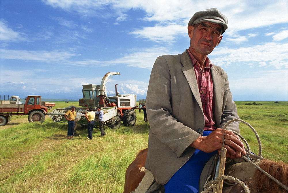 Portrait of a man, Anvar Tuunthush, a foreman, with farm machinery in the background on the north east shore of Lake Issyk-Kul, Kyrgyzstan, Central Asia, Asia