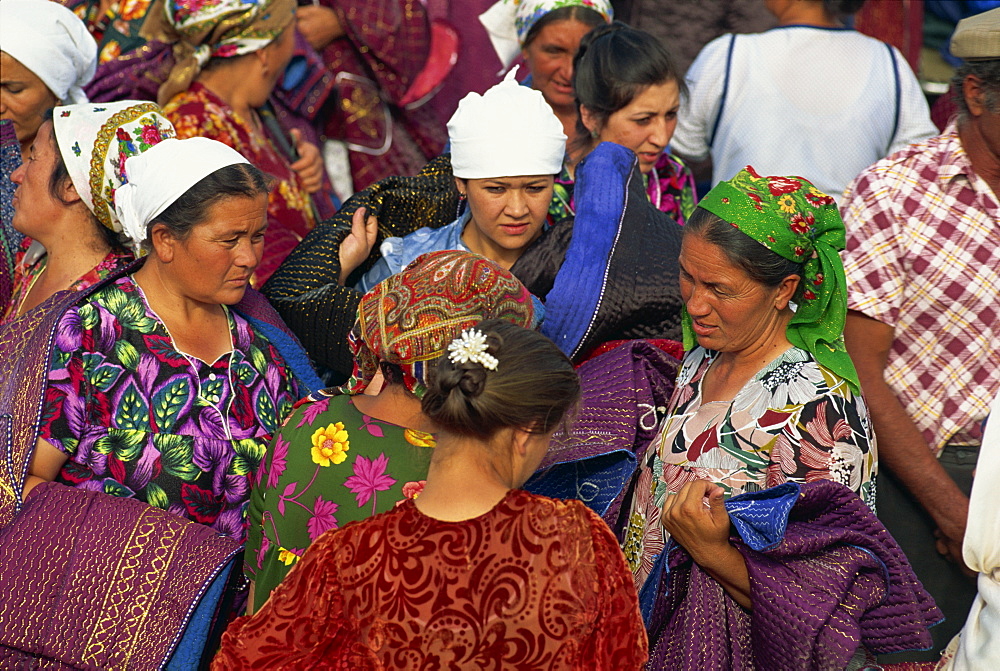 Women in bright dresses and head scarves in the new clothes market within the Old City wall of Bukhara, Uzbekistan, Central Asia, Asia