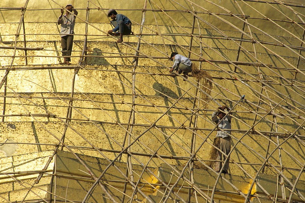 Workers on bamboo scaffolding applying fresh gold leaf to the Shwedagon Pagoda, Yangon (Rangoon), Myanmar (Burma), Asia