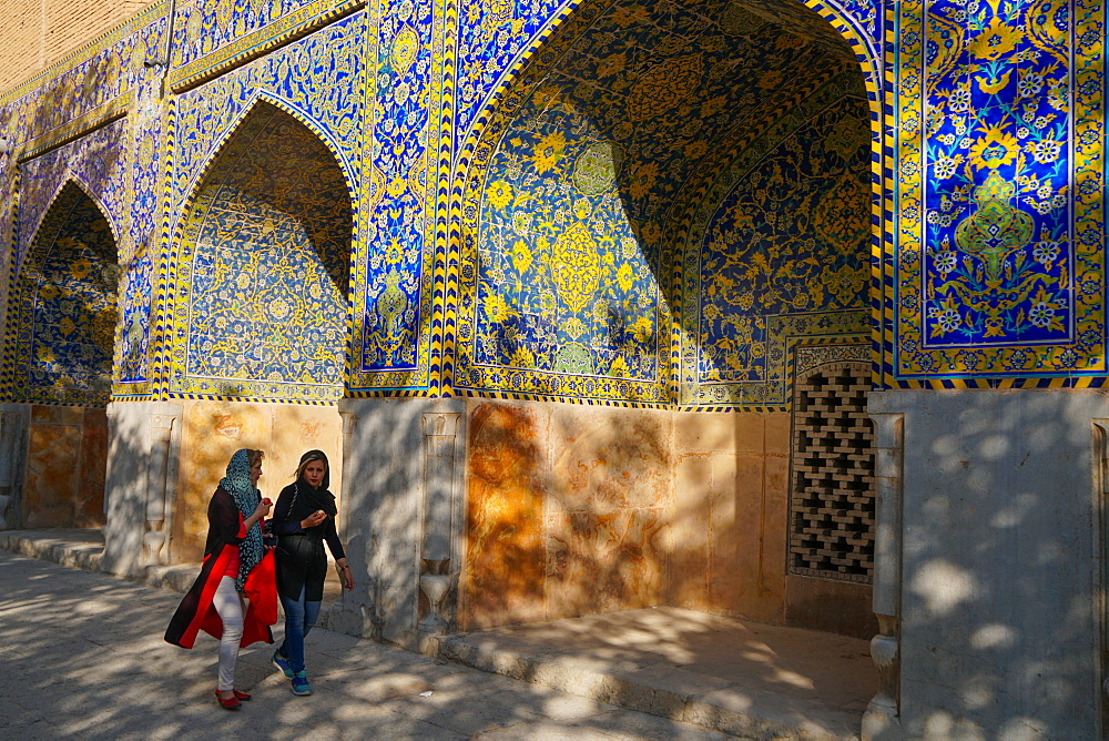 Two Iranian girls walking past courtyard walls, Imam Mosque, UNESCO World Heritage Site, Isfahan, Iran, Middle East