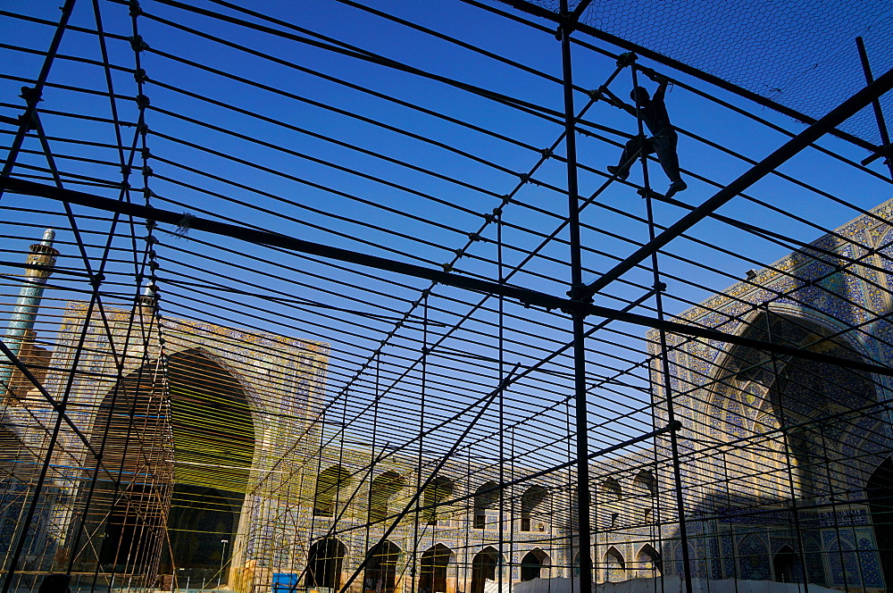 Silhouetted workman setting up marquee for special event in the courtyard of Imam Mosque, Isfahan, Iran, Middle East