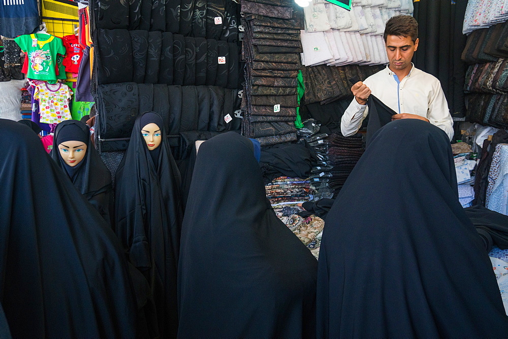 Chador merchant with customers and mannequins, bazaar, Qom, Iran, Middle East