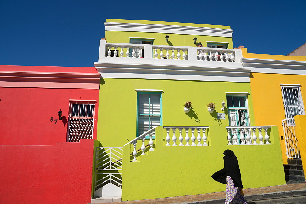 Silhouetted woman covered in black robe passes brightly coloured houses in Bo-Kaap, the Malaysian and Muslim area, Cape Town, South Africa, Africa