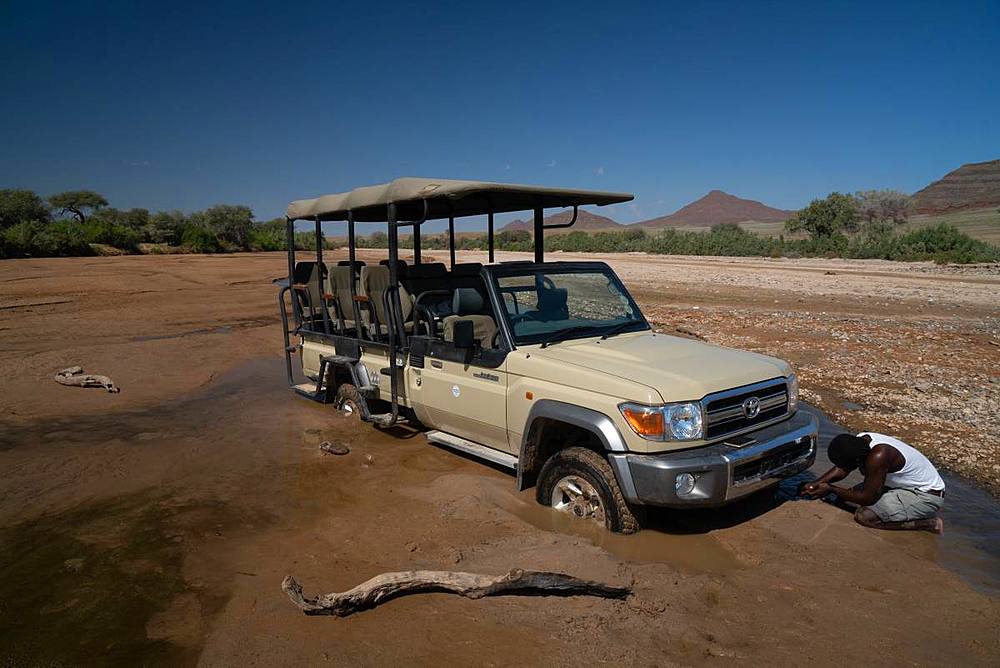 Guide tries to jack up safari vehicle stuck in the sand of Hoarusib Riverbed, Puros, north of Sesfontein, Nambia, Africa