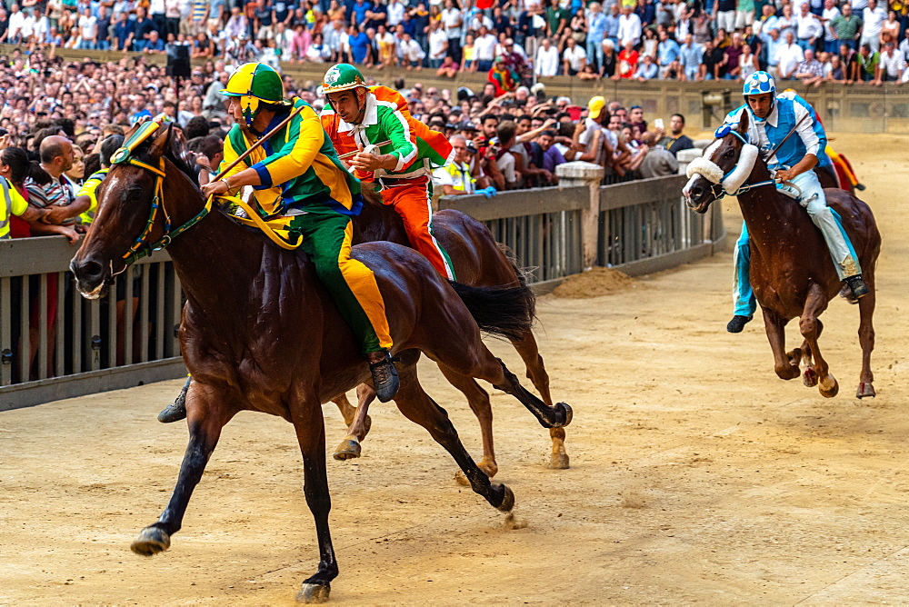 Jockeys in colourful outfits representing their respective neighbourhoods (contrade) vying for the lead at the Palio, Siena, Tuscany, Italy, Europe