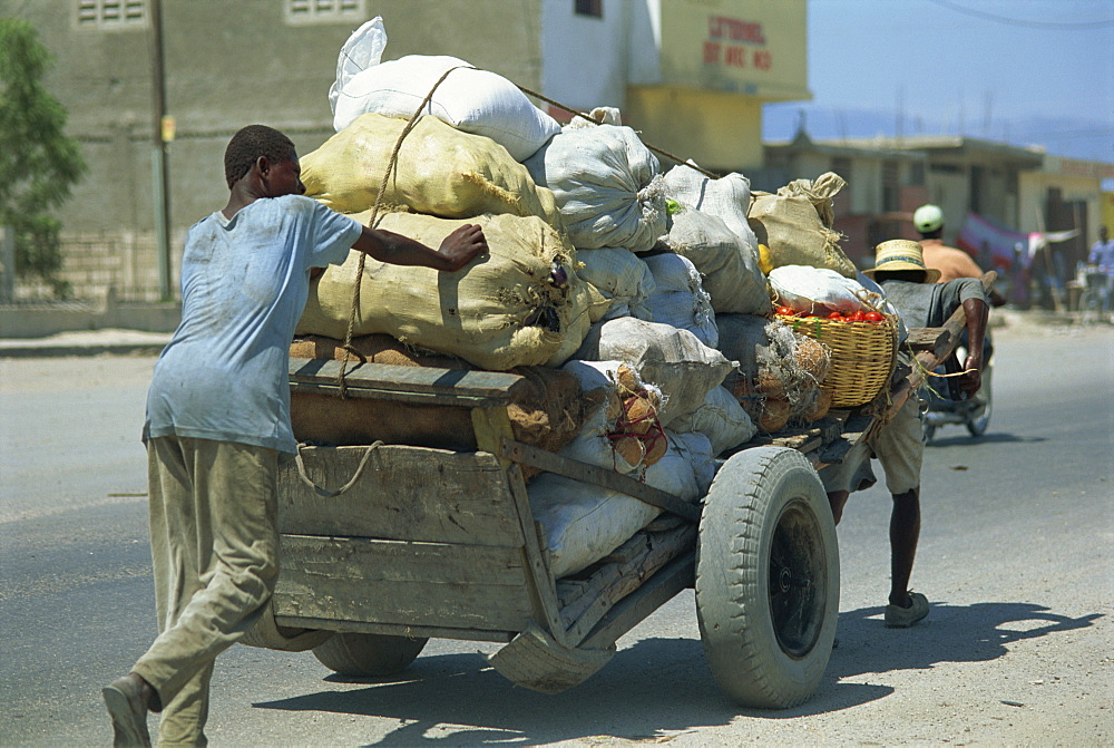 Men pushing and pulling heavily loaded cart along road, Port au Prince, Haiti, West Indies, Caribbean, Central America