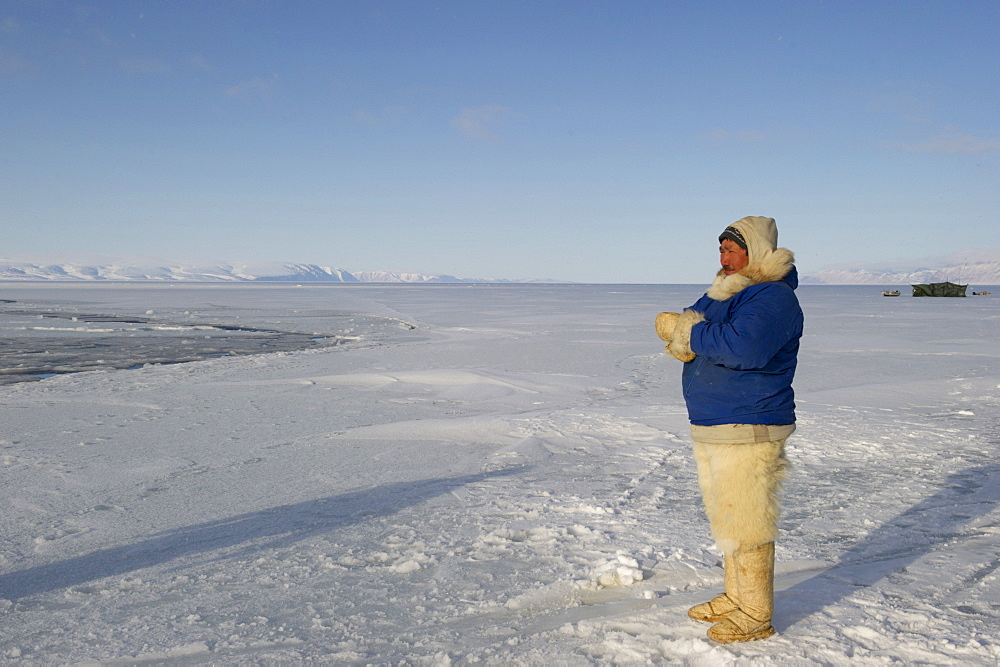 Inuit or Inughuit subsistence hunter with traditional clothing for winter and spring of seal skin boots (Kamiks), polar bear fur trousers, seal skin mitts and parka, Greenland, Denmark, Polar Regions