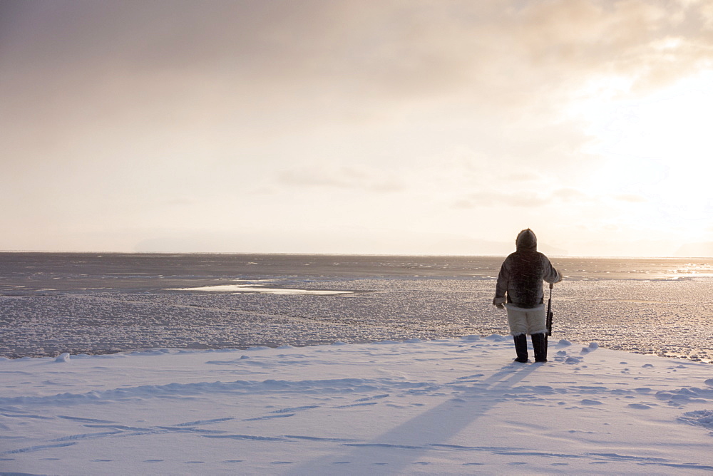 One of the last remaining Inughuit subsistence hunters, Naimanngitsoq Kristiansen, stands on watch with his rifle for marine mammals at the ice edge, Greenland, Denmark, Polar Regions