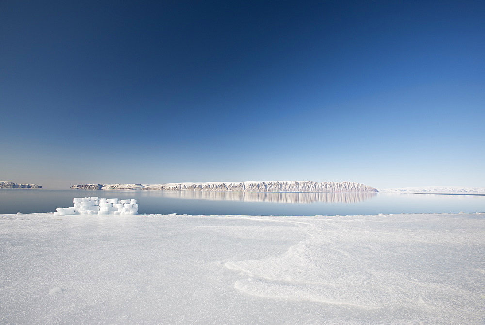 Hunting blind made from ice blocks at the Floe edge, the junction of sea ice and the ocean, Herbert Island in the background, Greenland, Denmark, Polar Regions