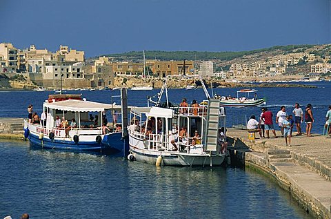 Tourists boarding boats from a jetty in St. Pauls Bay, Malta, Mediterranean, Europe