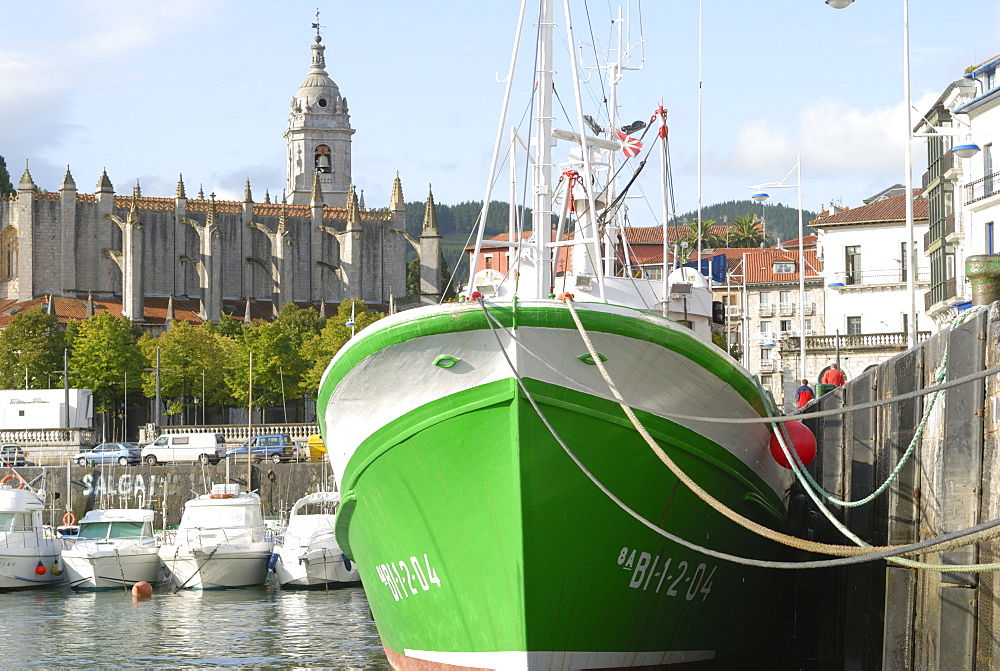 Old wooden fishing boat, and 15th century Gothic church of Santa Maria de la Asuncion, Lekeitio, Basque country, Euskadi, Spain, Europe