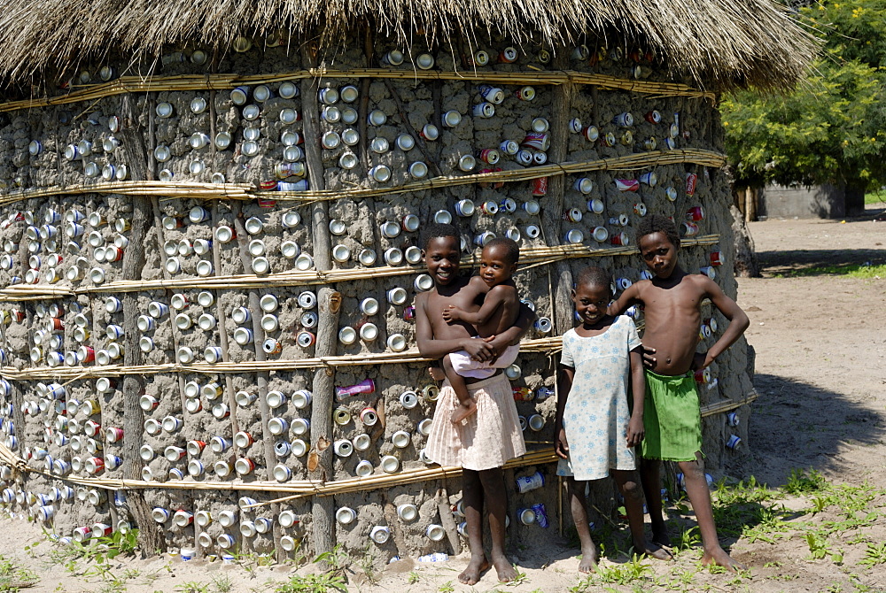 Recycling tins in traditional house building, and children, Botswana, Africa