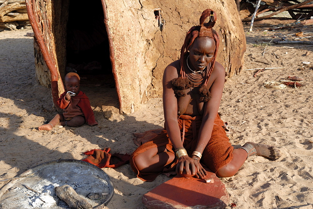 Woman of the Himba tribe grinding pigment for body decoration, Kaokoland, Namibia, Africa