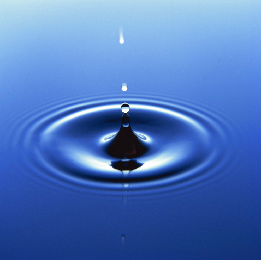 Water droplet hitting water surface creating ripples