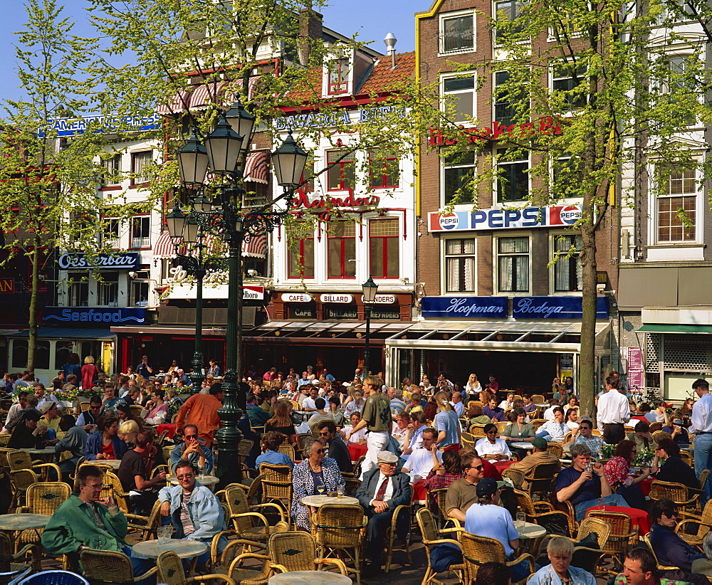 Tourists and locals at an open air cafe in Leidseplein, Amsterdam, Holland, Europe