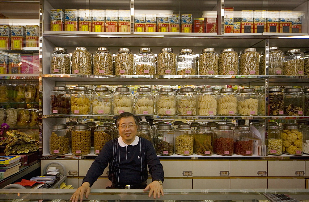 Man standing behind counter of a grocery shop, looking at camera, Hong Kong, China, Asia