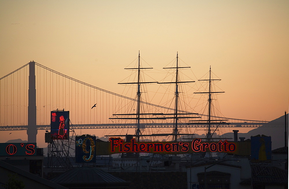 Fishermen's Grotto neon, with sailing ship Balclutha, and Golden Gate Bridge silhouetted against sky, San Francisco, California, United States of America, North America