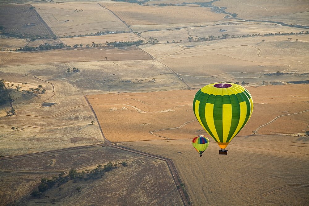 Aerial view of two hot air balloons floating over brown countryside near Northam in Western Australia, Australia, Pacific