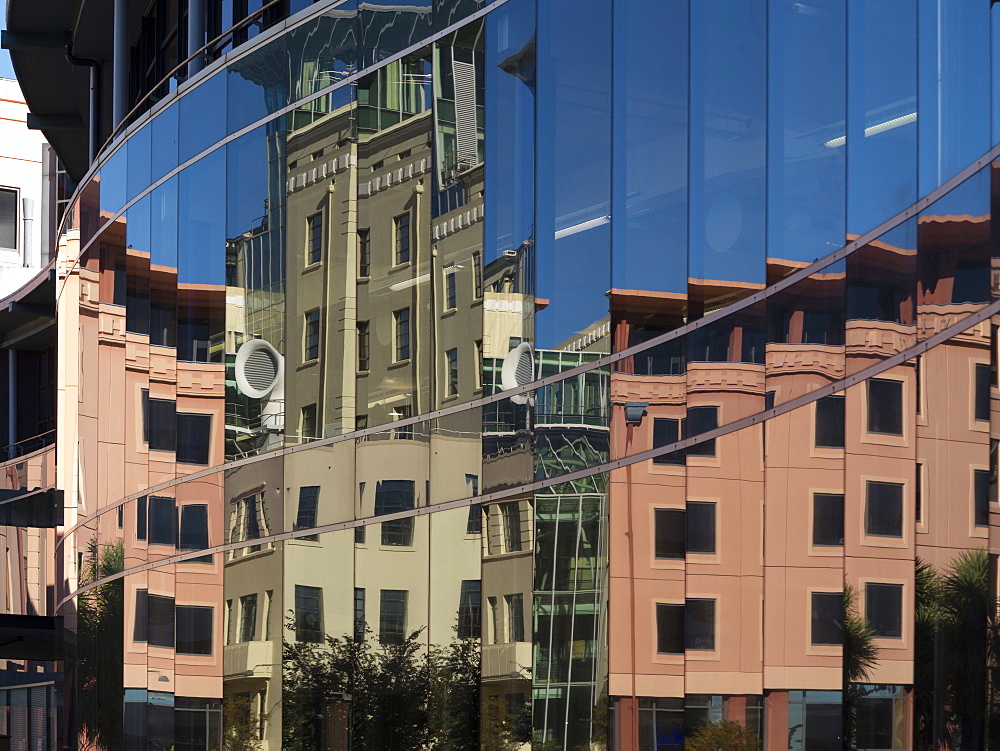 City council buildings in Civic Square reflecting in glass wall of public library, Wellington, North Island, New Zealand, Pacific