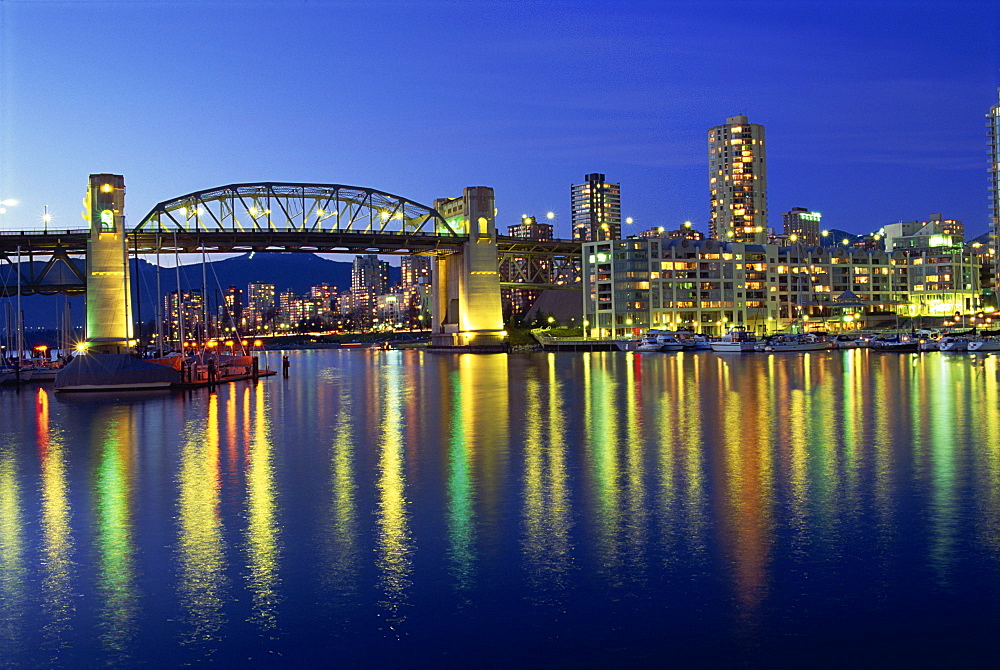 City lights reflected in the water of False Creek, below Burrard Bridge at night, in Vancouver, British Columbia, Canada