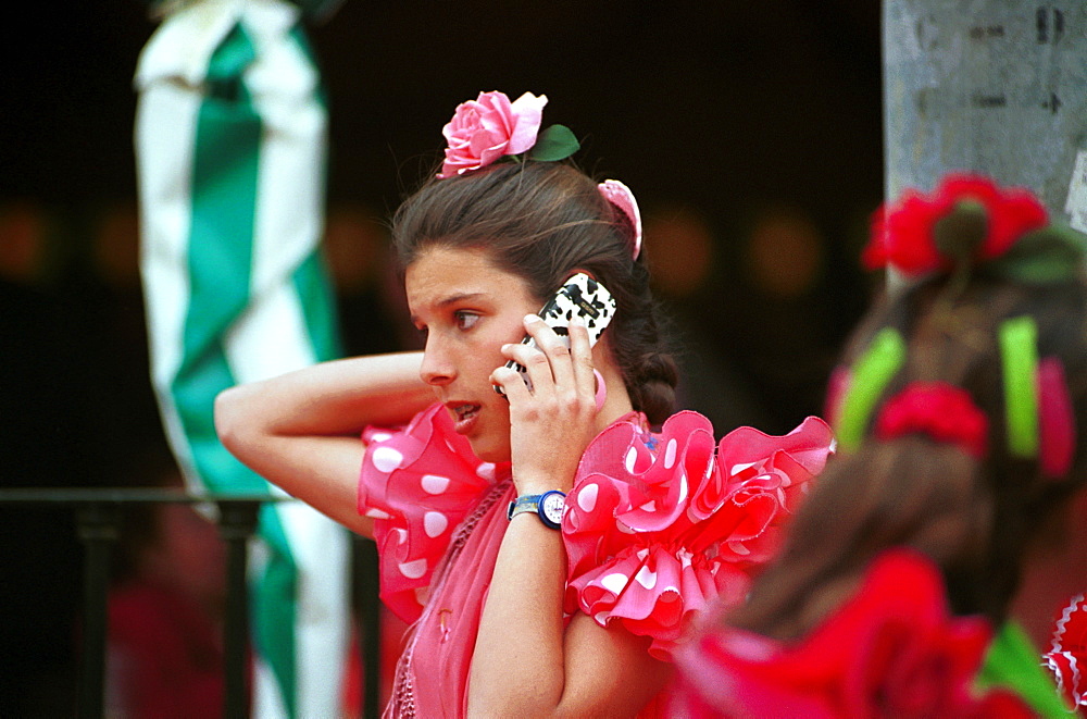 Seville - Spain - The Feria de Abril - Seville Fair - A girl in traditional costume making a call on her mobile phone 