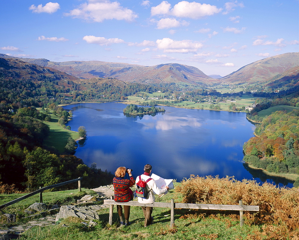 Couple resting on bench, viewing the lake at Grasmere, Lake District, Cumbria, England, UK 