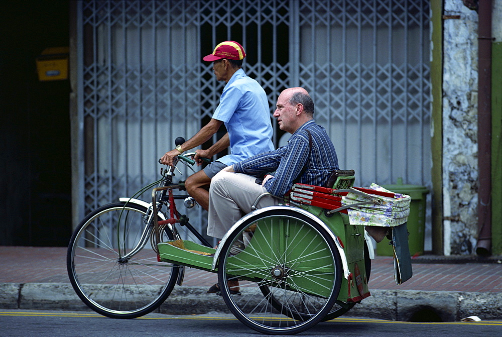 Western man riding as passenger in a cycle rickshaw in Singapore, Southeast Asia, Asia