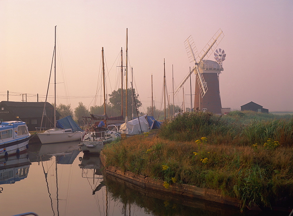 Horsey Wind Pump and boats moored on the Norfolk Broads at dawn, Norfolk, England, United Kingdom, Europe