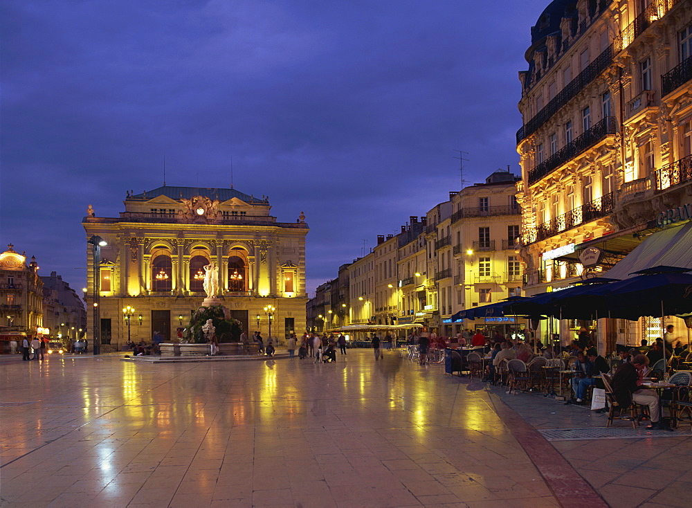 Pavement cafes on the Place de la Comedie and illuminated buildings in Montpellier, Languedoc Roussillon, France, Europe