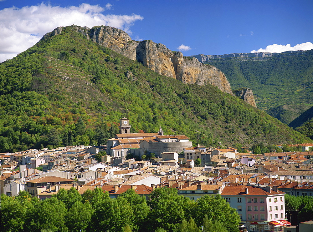 Houses and church with bell tower below a rocky hill at Digne les Bains, Alpes de Haute Provence, Provence, France, Europe