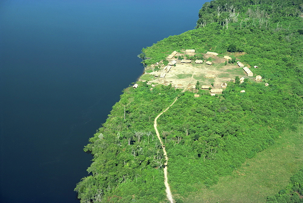 Aerial of a Xingu village and path beside a river in Brazil, South America