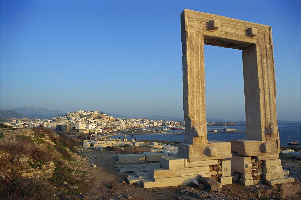 Roman arch at archaeological site with sea and village in the background, on Naxos, Cyclades Islands, Greek Islands, Greece, Europe